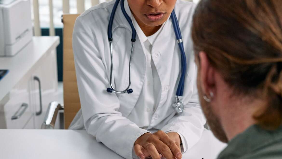 Médica discute prontuário com paciente em consulta