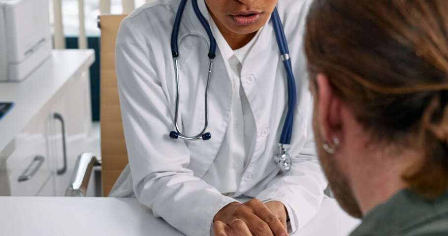 Médica discute prontuário com paciente em consulta