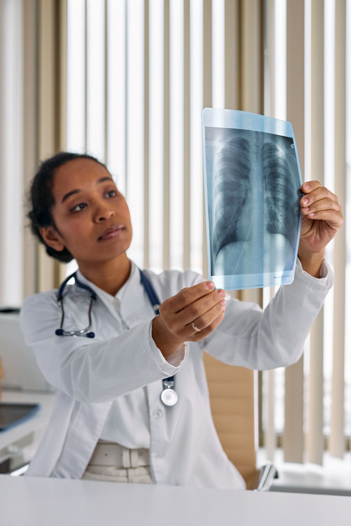 Médico analisa uma radiografia de tórax em ambiente clínico