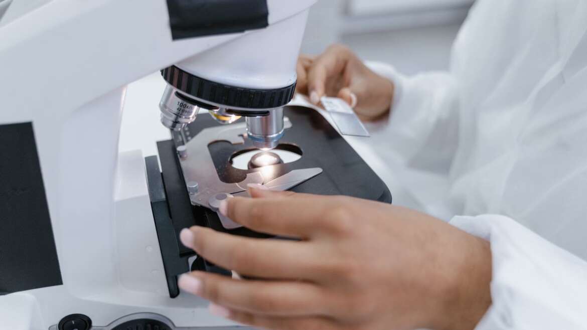 Cientista utiliza microscópio para análise de amostra em laboratório