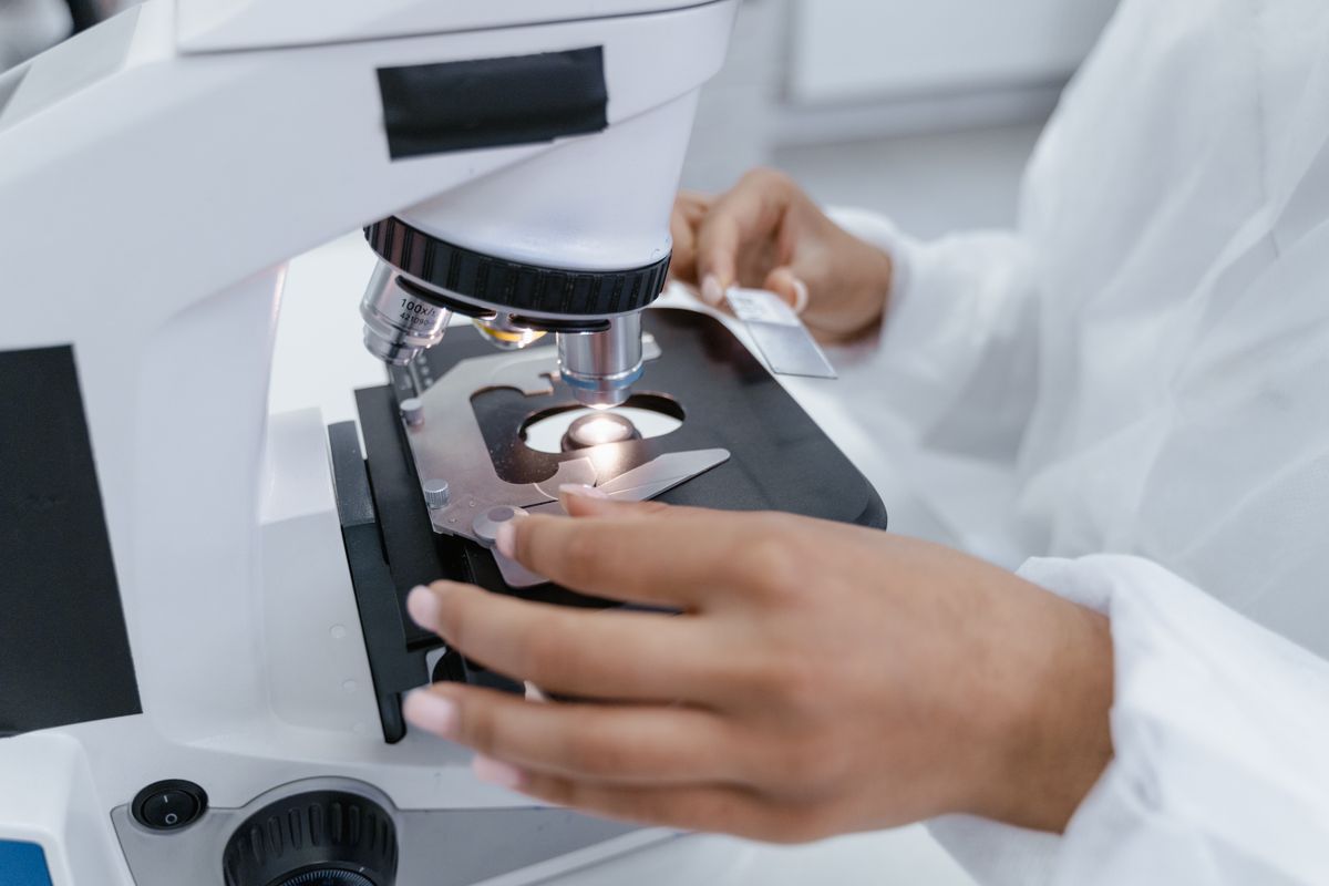 Cientista utiliza microscópio para análise de amostra em laboratório