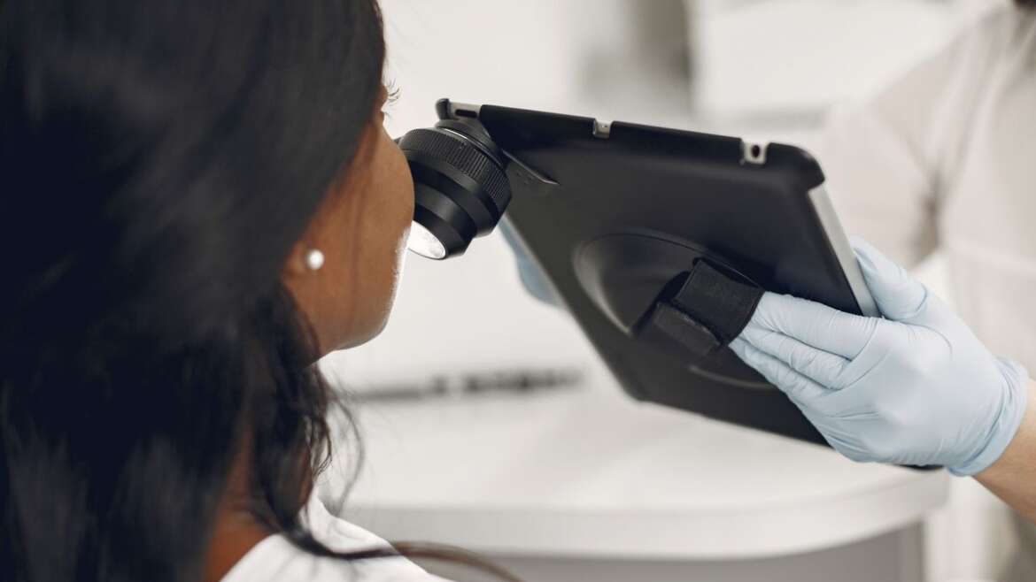 Dermatologista examina a pele de um paciente com dermatoscópio