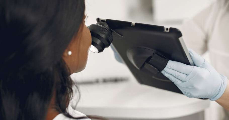Dermatologista examina a pele de um paciente com dermatoscópio