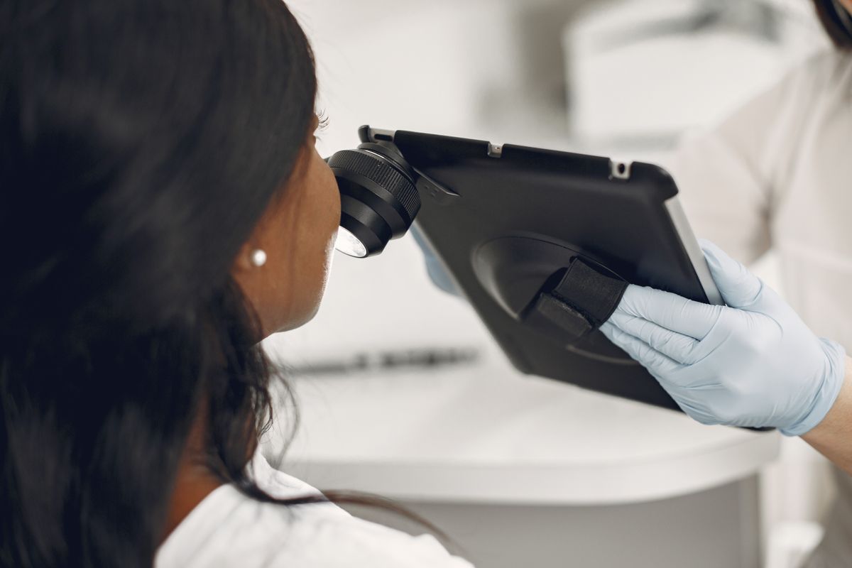 Dermatologista examina a pele de um paciente com dermatoscópio