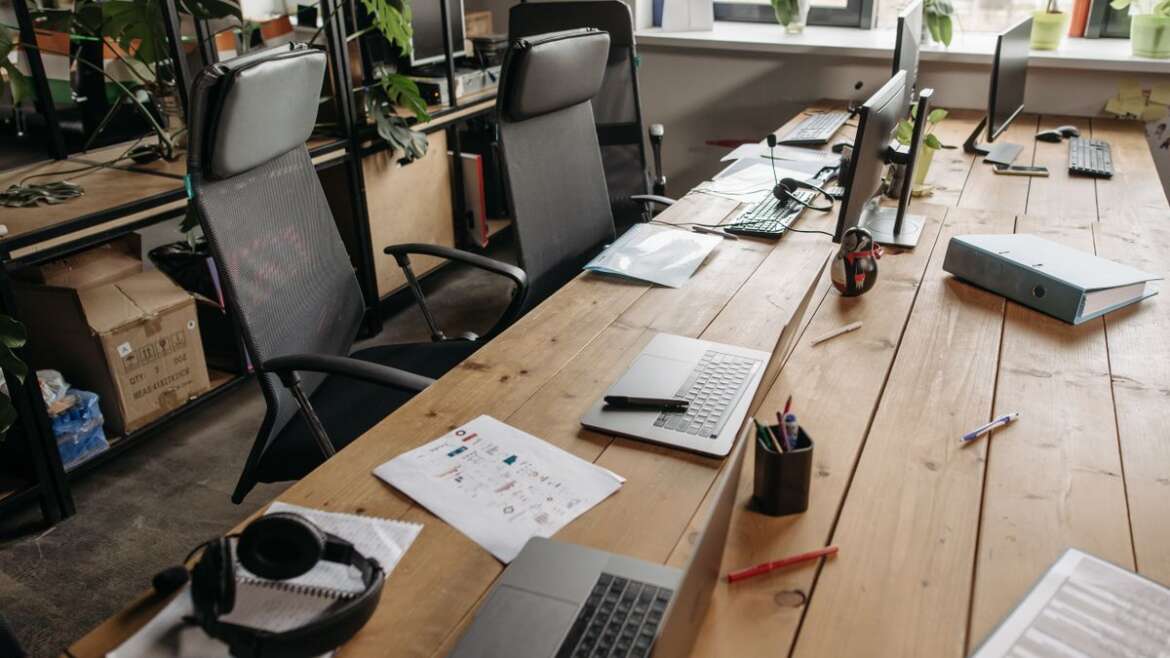 Mesa de escritório com documentos, computador e cadeiras, representando a administração do espólio pelo inventariante.