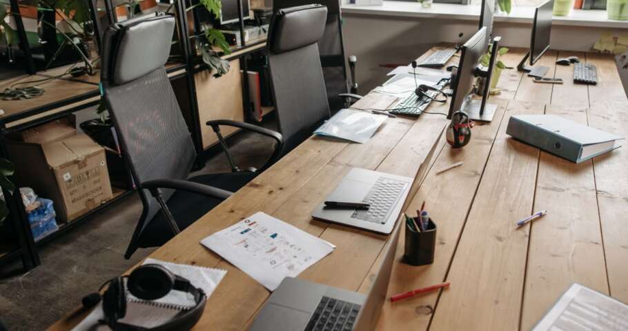 Mesa de escritório com documentos, computador e cadeiras, representando a administração do espólio pelo inventariante.