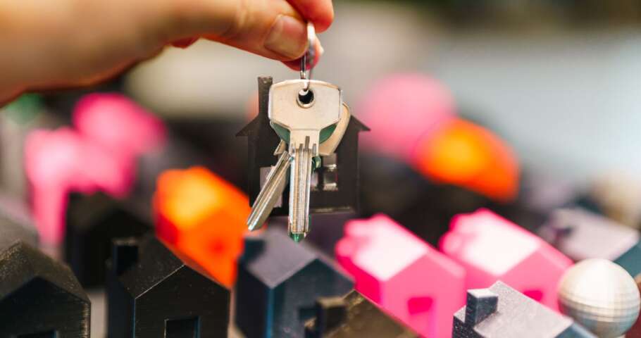 Molho de chaves suspenso sobre miniaturas de casas, representando o imóvel da herança ocupado por um único herdeiro.