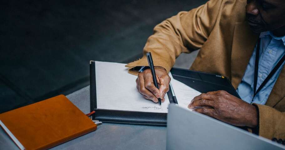 Pessoa assinando documentos sobre a mesa, tema do inventário quando um herdeiro se recusa a assinar.