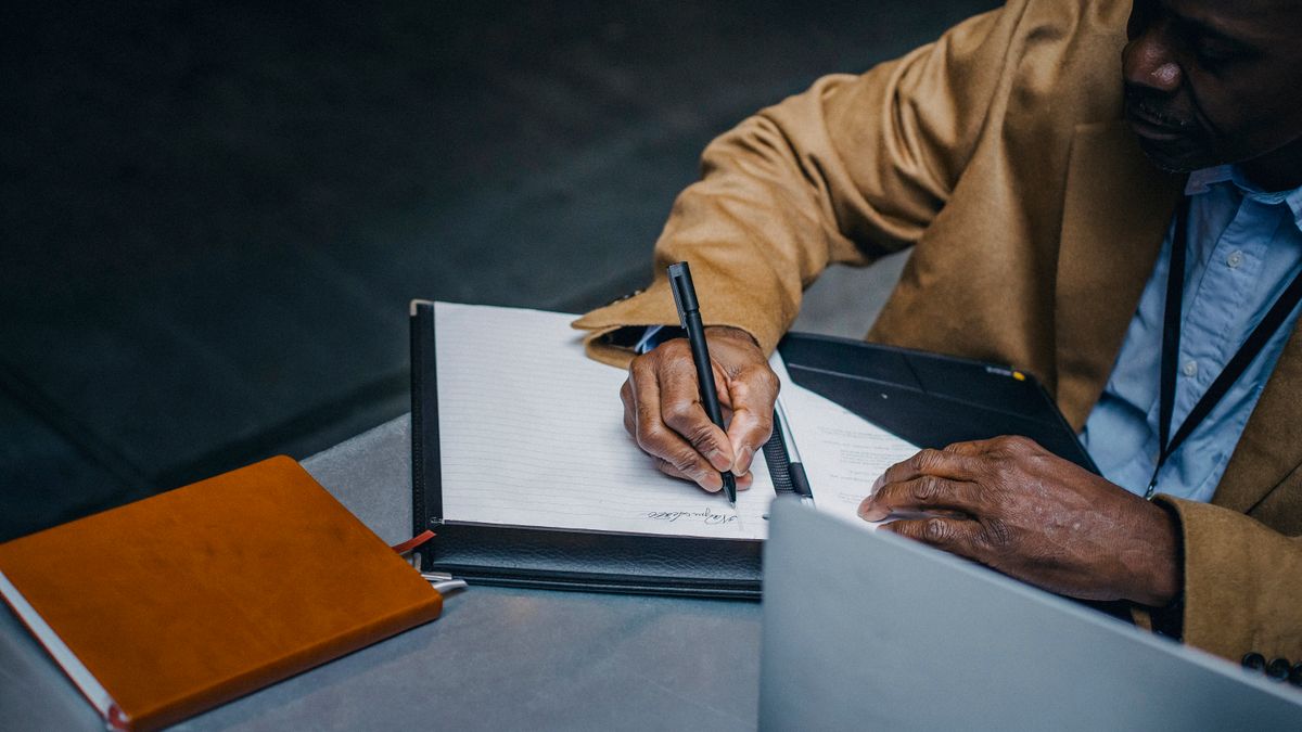Pessoa assinando documentos sobre a mesa, tema do inventário quando um herdeiro se recusa a assinar.
