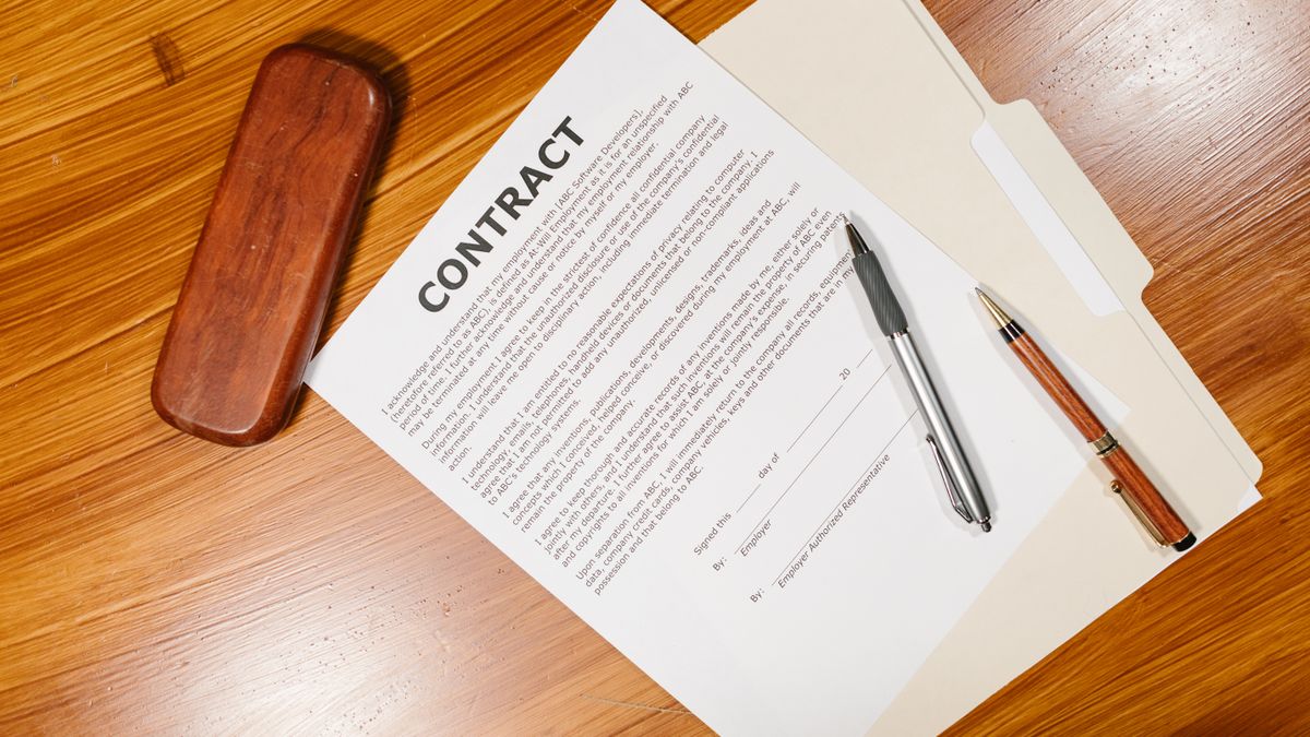 Documento de contrato com caneta sobre a mesa de madeira, referência ao aluguel do imóvel da herança.