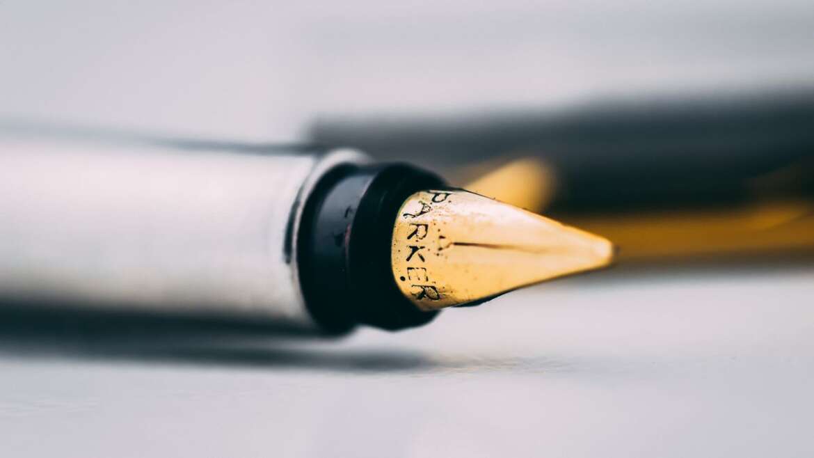 Caneta-tinteiro em detalhe sobre a mesa, representando a alteração e a revogação de um testamento.