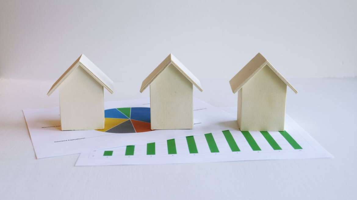 Miniaturas de casas sobre um gráfico impresso, representando a venda de imóvel entre pai e filho.
