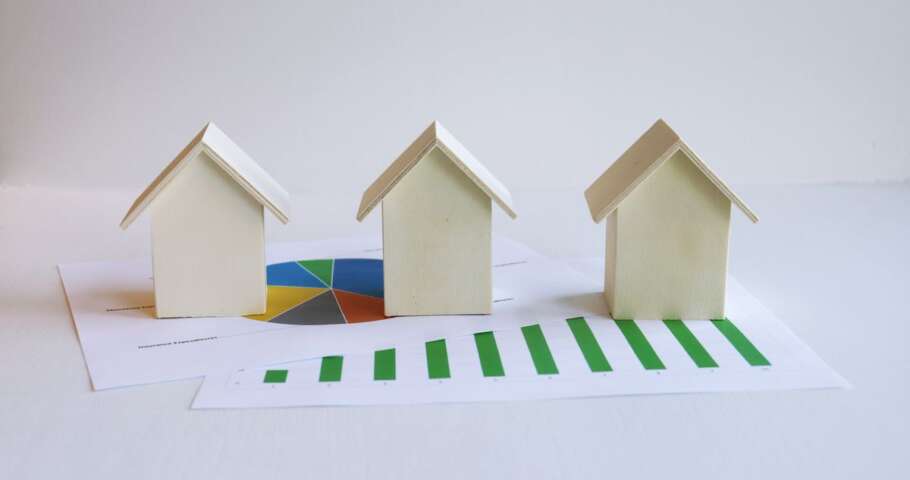 Miniaturas de casas sobre um gráfico impresso, representando a venda de imóvel entre pai e filho.