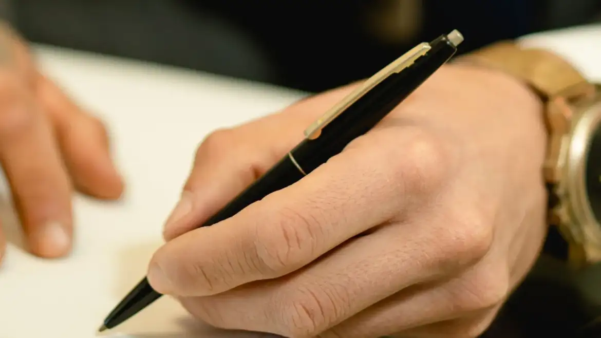 Pessoa assinando um documento com caneta, representando testamento e planejamento sucessório